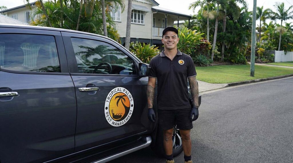 Kurt from Tropical Palms standing beside the branded service vehicle in a Cairns suburb ready for pest control work.